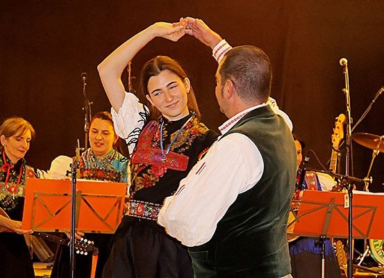 Ein Paar tanzt vor einer Band mit Gitarren, Trommeln und einer Becken auf der Bühne.