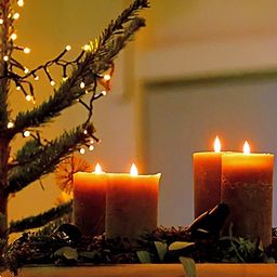 Ein kleiner Weihnachtsbaum mit brennenden Kerzen und Lichtern in einer Ecke.