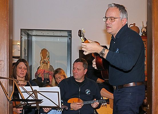 Eine Gruppe von Musikern tritt drinnen auf. Ein Mann spielt Balalaika. Eine Frau hält eine Geige.