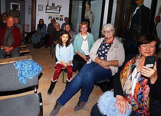 Eine Gruppe von Menschen, darunter ein älterer Mann, ein junges Mädchen und mehrere Frauen, sitzen in einem Raum, möglicherweise bei einer Versammlung oder einem Treffen.