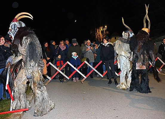 Menschen in Kostümen stehen bei Nacht vor einer Menge in der Nähe einer Barriere.