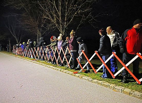 Eine nächtliche Szene, in der Menschen hinter Barrieren stehen, wahrscheinlich warten sie auf eine Veranstaltung oder Show.