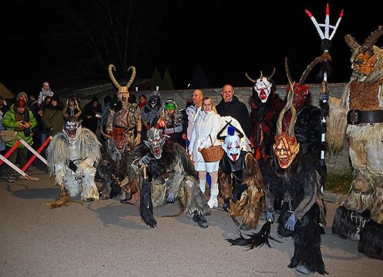 In der Nacht stehen eine Gruppe von Menschen in Monsterkostümen und Masken vor einer Wand, möglicherweise für eine Halloween-Veranstaltung.