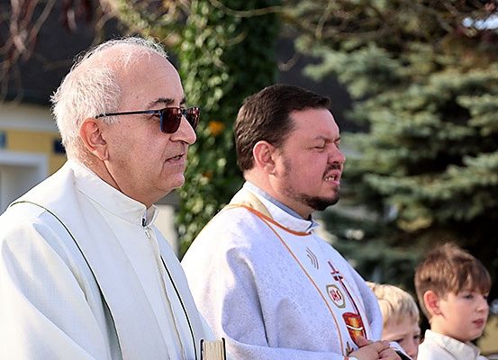 Zwei Priester stehen nebeneinander, möglicherweise während einer Zeremonie, mit mehreren Kindern im Hintergrund.