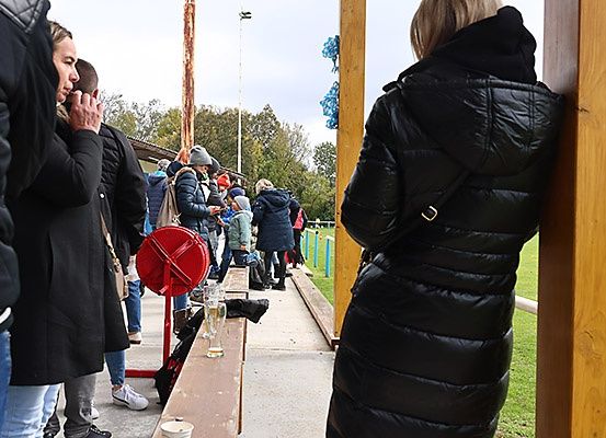 Eine Gruppe von Menschen in warmer Kleidung steht in einer Schlange an einem Essensstand, während andere sitzen und sich unterhalten.