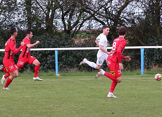 Fußballspieler in roten und weißen Trikots rennen auf einem Feld. Der Spieler in Rot mit der Nummer 8 tritt den Ball.