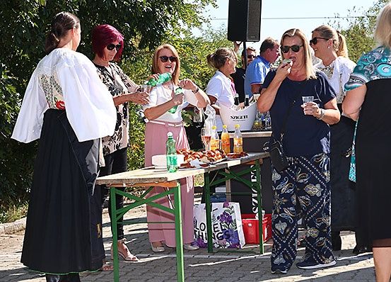 Eine Gruppe von Frauen steht um einen Tisch mit Essen und Getränken. Eine Frau isst ein Sandwich.