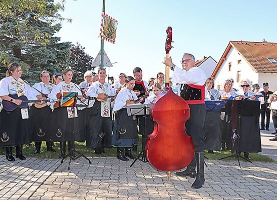 Eine Band in traditioneller Kleidung spielt mit verschiedenen Instrumenten, einschließlich eines Cellos, im Freien.