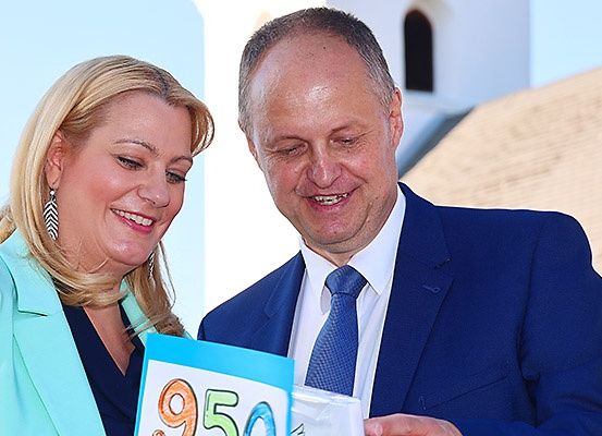 Ein Mann und eine Frau lächeln und betrachten ein Papier mit der Nummer 950.
