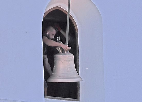Ein Mann klettert in einen Glockenturm und stellt eine große Glocke ein, möglicherweise in Vorbereitung auf das Läuten.