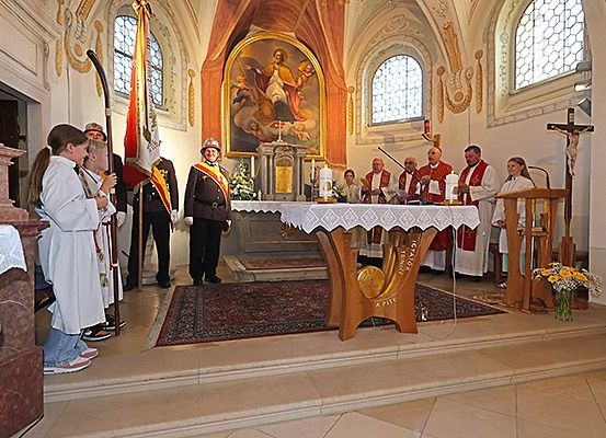 Eine Kirchenzeremonie mit Priestern und Ministranten. Eine Person in Uniform steht in der Nähe des Altars. Kinder in weißen Gewändern stehen links.