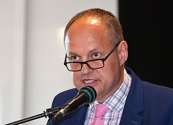 Ein Mann mit Brille und Anzug spricht in ein Mikrofon am Rednerpult.