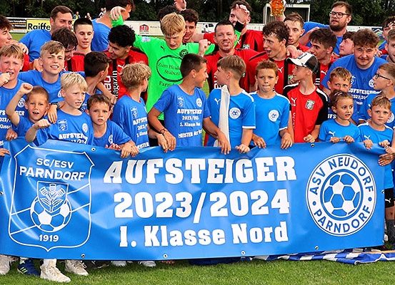 Eine Gruppe von Fußballspielern und Trainern posiert für ein Foto auf dem Feld und hält ein blaues Banner mit den Worten 'Aufsteiger 2023/2024' und 'I. Klasse Nord'.