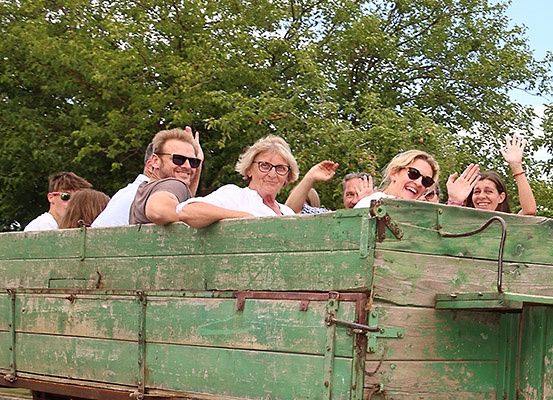 Eine Gruppe von Menschen mit Sonnenbrillen fährt an einem sonnigen Tag in einem grünen Truck.