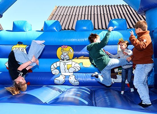 Eine Gruppe von Kindern spielt in einem blauen aufblasbaren Sprunghaus mit Comic-Charakter-Designs.