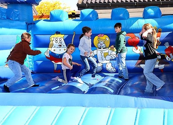 Fünf Kinder spielen in einem großen aufblasbaren Schloss mit Cartoon-Charakteren darauf.
