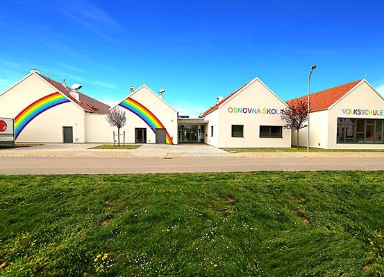 Eine Reihe von drei weißen Gebäuden mit roten Dächern, von denen eines einen Regenbogen an seiner Wand hat.