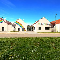 Eine Reihe von drei weißen Gebäuden mit roten Dächern, von denen eines einen Regenbogen an seiner Wand hat.