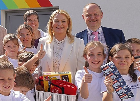 Eine Gruppe lächelnder Kinder und Erwachsener posiert für ein Foto mit einem Korb voller Spielzeug und Geschenken.