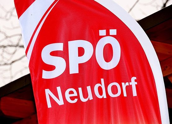 Ein roter Banner mit weißen Buchstaben, die 'SPO Neudorf' sagen, wird vor einer Holzstruktur angezeigt.