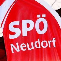 Ein roter Banner mit weißen Buchstaben, die 'SPO Neudorf' sagen, wird vor einer Holzstruktur angezeigt.