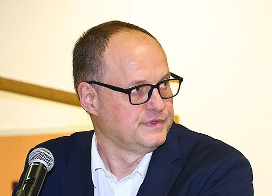 Ein Mann mit Brille und Anzug spricht in ein Mikrofon.