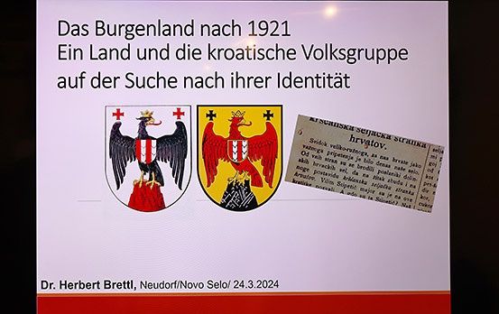 Präsentationsfolie von Dr. Herbert Brettl über die Region Burgenland nach 1921, mit Fokus auf die Identitätssuche der kroatischen Volksgruppe, mit Wappensymbolen und einem Auszug aus einem historischen Dokument.