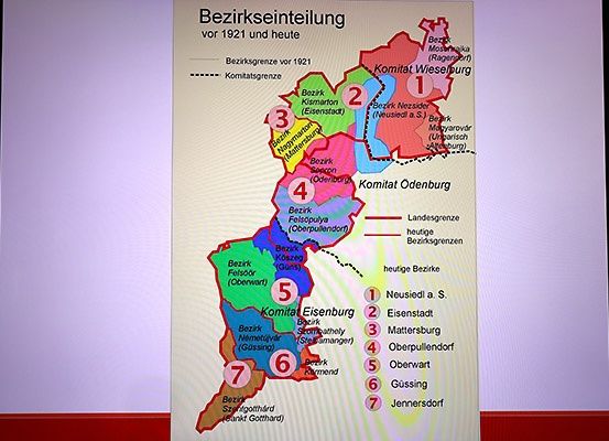 Eine Karte, die die Bezirkseinteilung vor 1921 und heute zeigt. Die Karte ist in farbige Abschnitte unterteilt, mit Bezeichnungen für jeden Bezirk. Bezirksgrenzen sind markiert, und es gibt aktuelle und historische Grenzen.