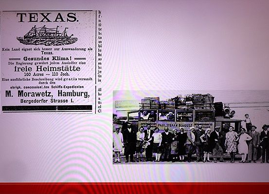 Ein Werbeplakat für Texas mit einem Bild eines Schiffes und Text, der Siedlern kostenloses Land anbietet. Unter dem Plakat ein Schwarz-Weiß-Foto von Menschen, die vor einem Bus stehen.