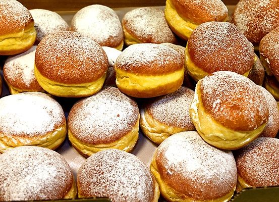 Eine Nahaufnahme einer Schachtel voller Beignets, goldenbraune Teigwaren mit Puderzucker bestreut.