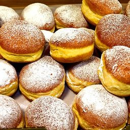 Eine Nahaufnahme einer Schachtel voller Beignets, goldenbraune Teigwaren mit Puderzucker bestreut.
