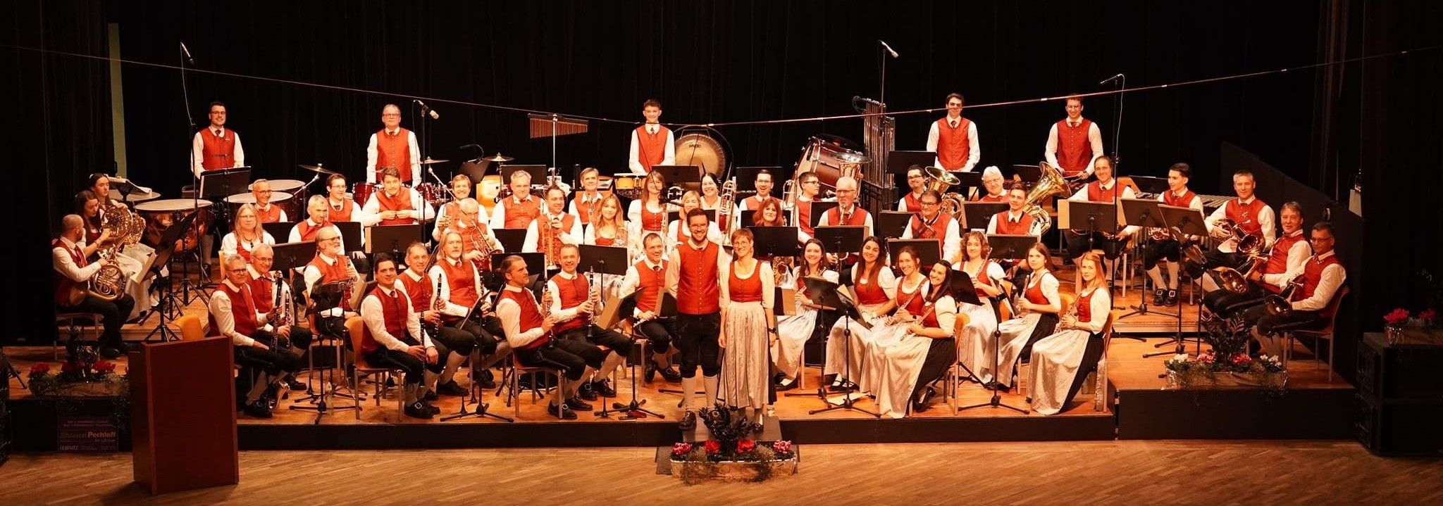 Eine Gruppe von Musikern in traditioneller Kleidung tritt mit Musikinstrumenten auf einer Bühne auf.