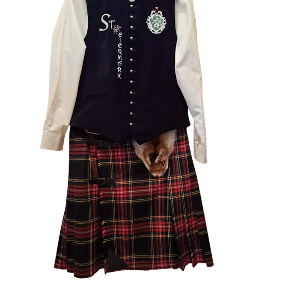 Ein Kilt mit Tartanmuster und eine Weste mit dem Wort 'Stirmark'. Ein Frack ist über dem Kilt getragen.