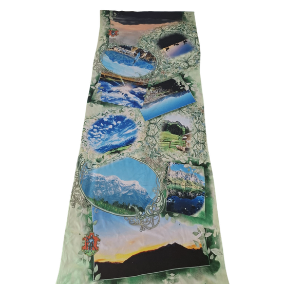 Ein Stoff mit einer Collage verschiedener Landschaften, darunter Berge, Wasser und einen Sonnenuntergang, alles auf einem grünen Hintergrund.