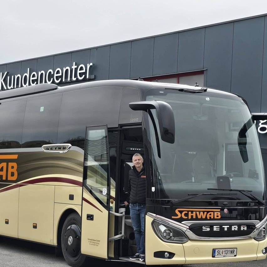 A man stands in the open door of a large bus, branded Schwab, parked in front of a building labeled Kundencenter.