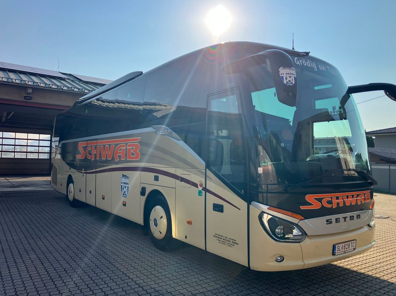 Ein weißer und schwarzer Bus mit roten und schwarzen Akzenten steht auf einem Parkplatz. Das Wort Schwab ist auf der Seite geschrieben.