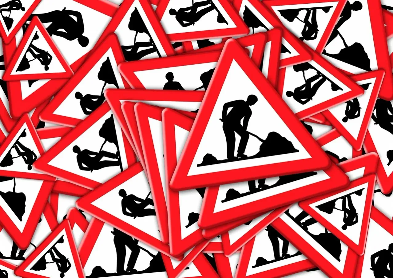 Eine Sammlung roter dreieckiger Verkehrsschilder, die Arbeiter in verschiedenen Posen zeigen, alle vor einem weißen Hintergrund.