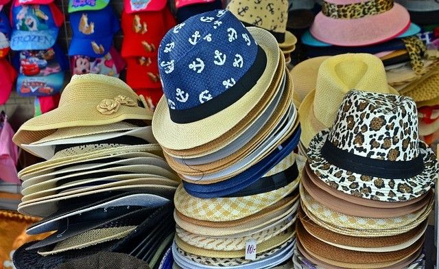 Ein Laden zeigt eine Vielzahl von Hüten, darunter einen blauen mit Ankerdesigns, einen rosafarbenen und einen mit Leopardenmuster.