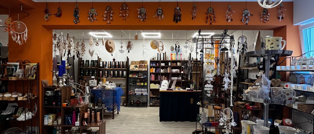 A store interior with tiled floors, shelves of products, and decorative items hanging from the ceiling. Various items are displayed on shelves and tables.