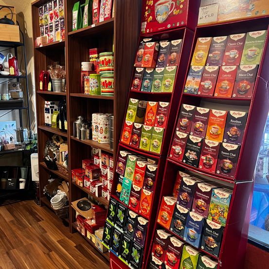 Ein Holzladen-Interieur mit Holzregalen auf beiden Seiten, gefüllt mit verschiedenen Tees und anderen Produkten.