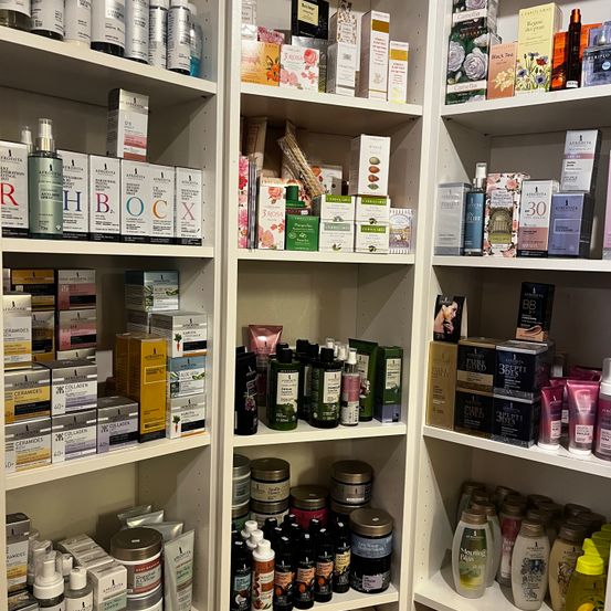 Ein großer Regal mit mehreren Regalen voller verschiedener Kosmetikprodukte. Sie sind ordentlich angeordnet und scheinen zum Verkauf zu stehen.