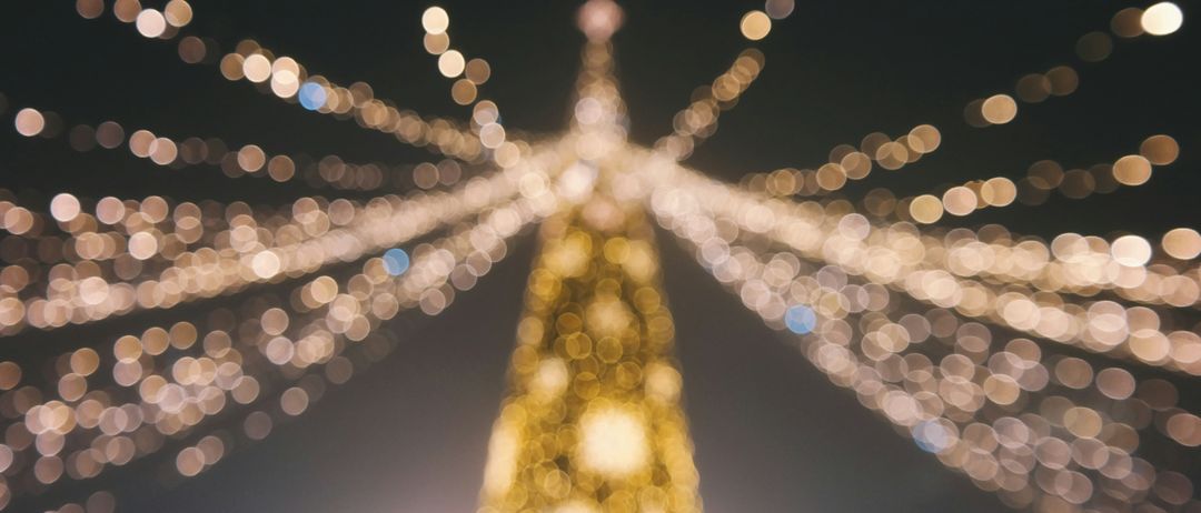 Ein Nahaufnahme einer goldenen Weihnachtsbaums, geschmückt mit funkelnden Lichtern, die eine warme und festliche Atmosphäre schaffen. Der Hintergrund ist dunkel, nur die Lichter erhellen den Baum.