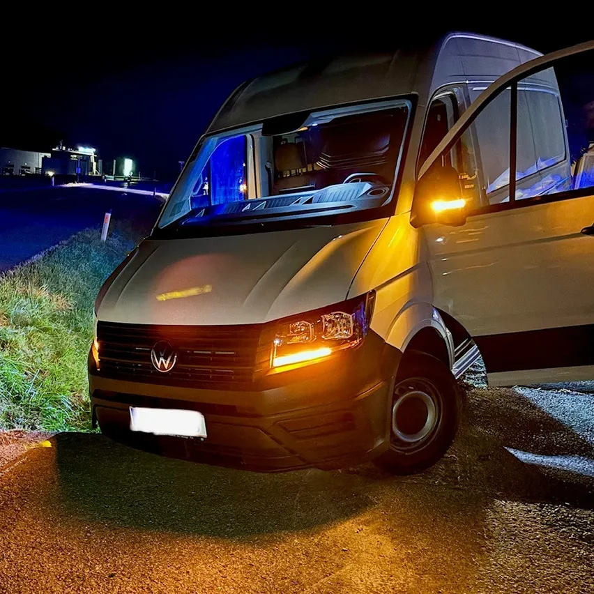 Ein Volkswagen-Transporter mit offenen Türen auf einer Straße bei Nacht.
