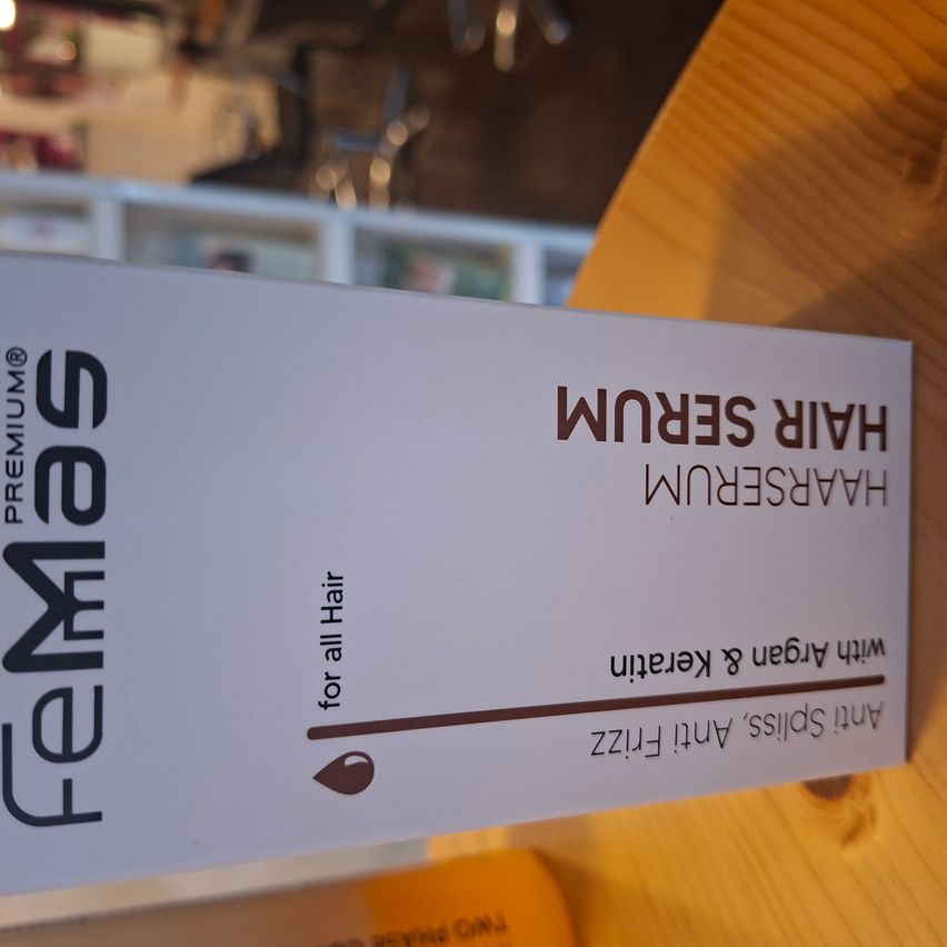 Eine weiße Schachtel mit schwarzem Text, betitelt 'KERATIN SILK' von 'FEMMES PREMIUM', steht auf einem Holztisch. Die Schachtel ist für alle Haartypen.