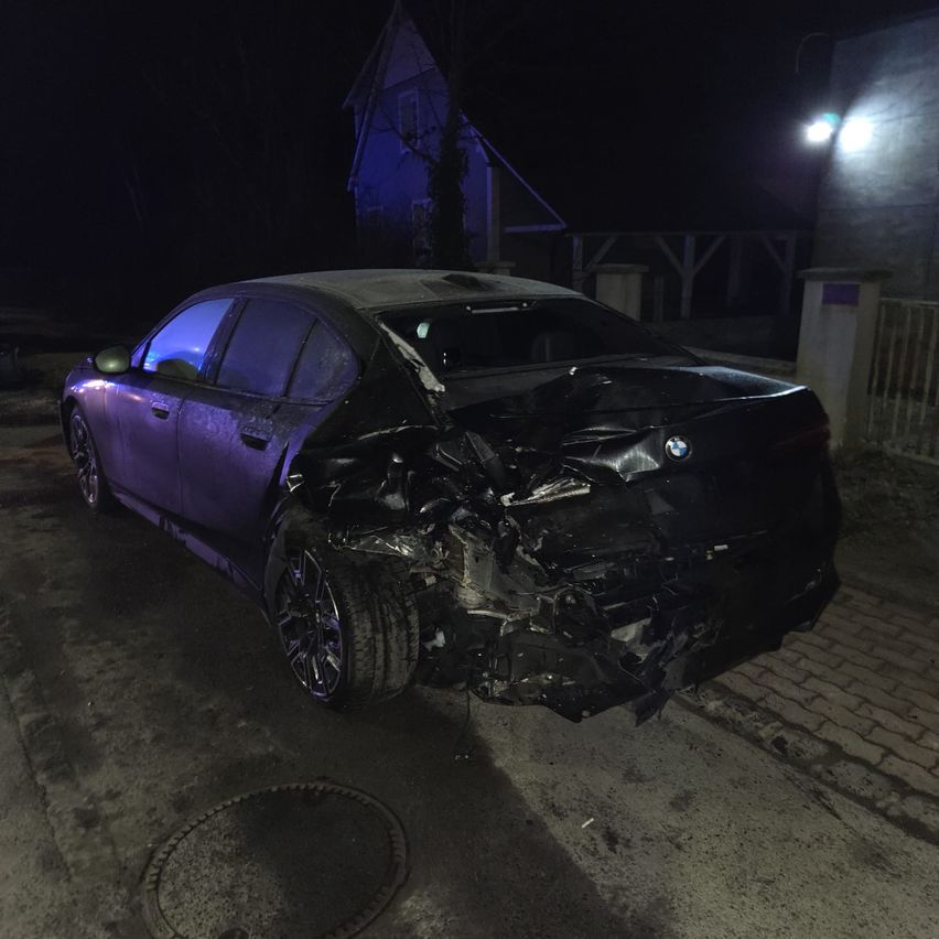 Ein lilafarbener BMW ist nachts auf der Straße geparkt und weist erhebliche Schäden an der Front auf.