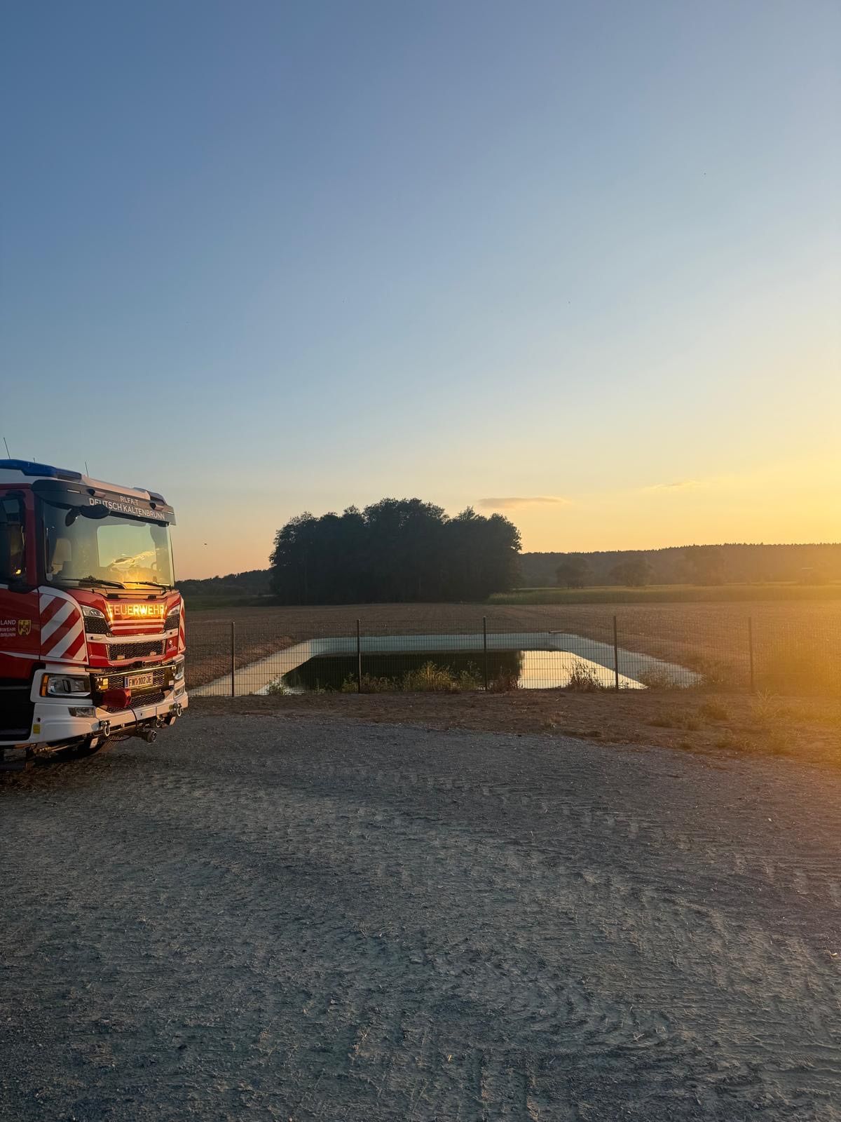 Feuerwehr Deutsch-Kaltenbrunn mit Löschwasserbehälter und Feld bei Sonnenuntergang