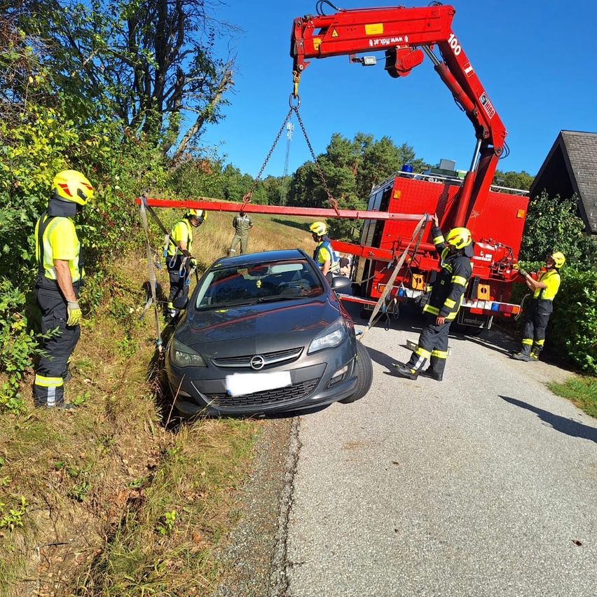 Feuerwehrleute benutzen einen Kran, um ein Auto von der Straßenseite zu heben.