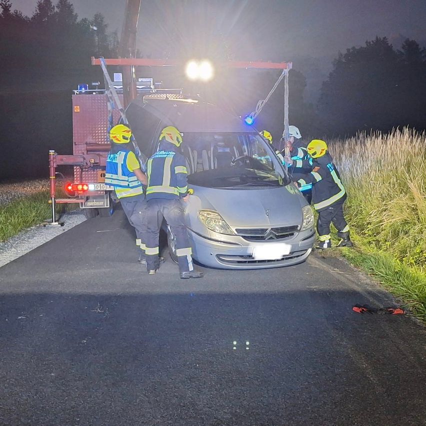 Feuerwehrleute in Schutzkleidung retten einen Van nachts von der Straßenseite.