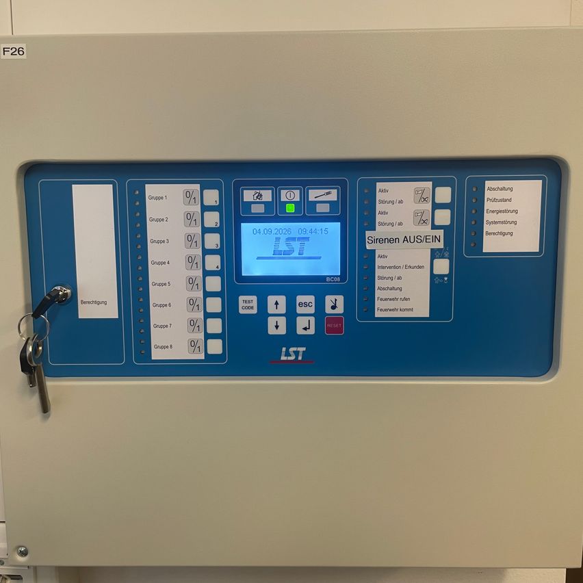 Ein elektronisches Gerät mit einer blau-weißen Schnittstelle. Es hat ein digitales Display, das Datum und Uhrzeit anzeigt, sowie mehrere Tasten und Schalter.