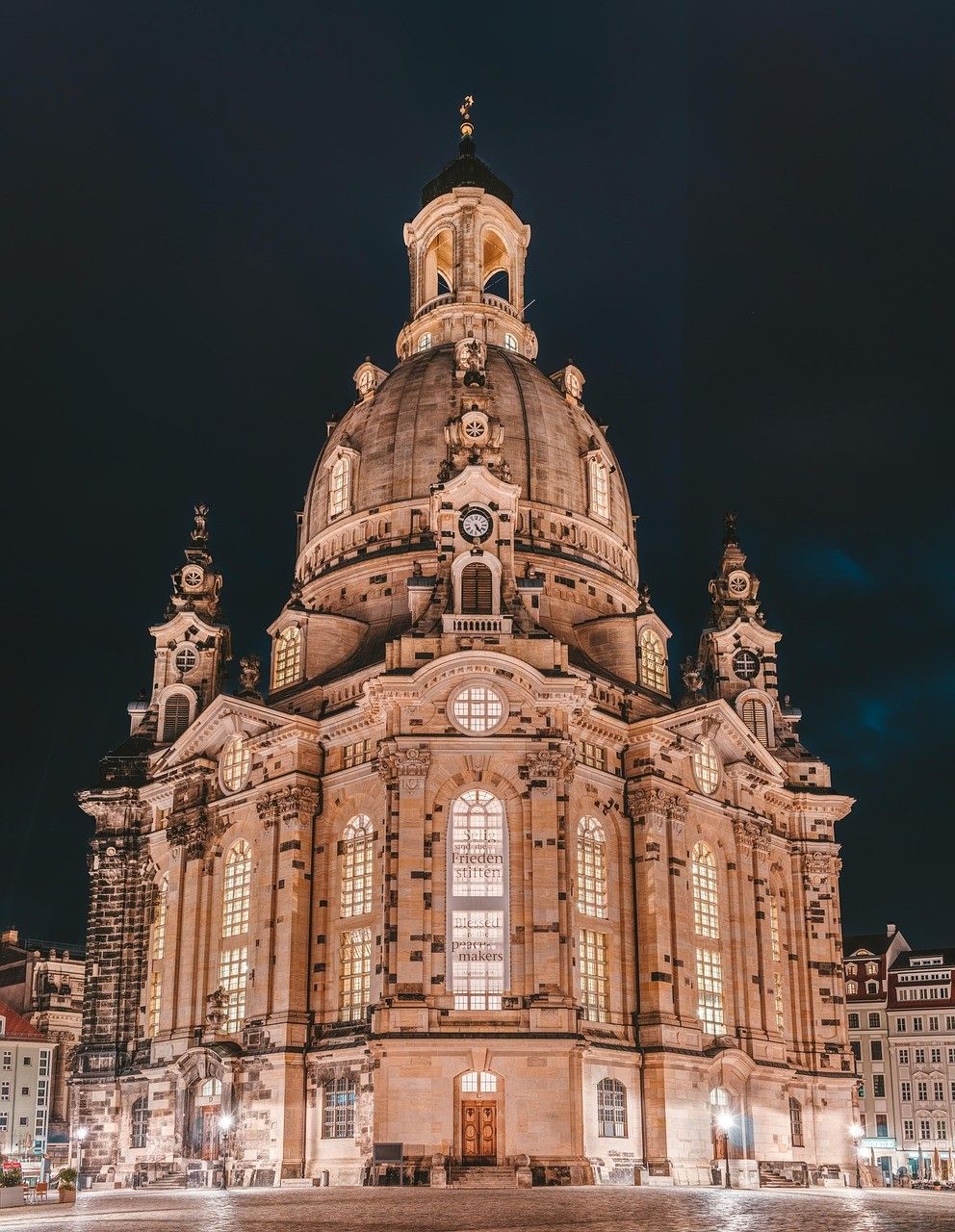 A nighttime view of Frauenkirche, a baroque-style church in Dresden with a dome and illuminated windows.